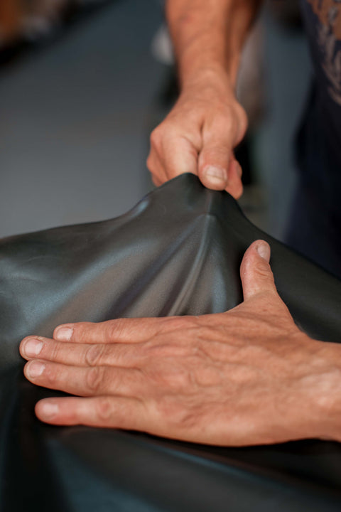 Close-up of a person's hands stretching a black leather piece to show its elasticity.